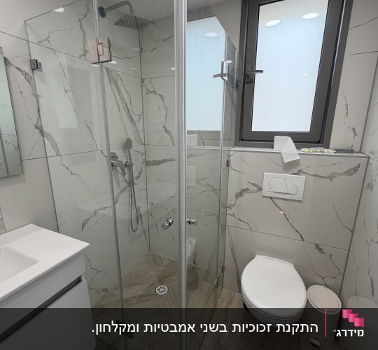 חדר אמבטיה עם מקלחון זכוכית ושירותים